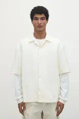 Camisa de manga corta color crema, de corte holgado, con cuello resort y cierre frontal con botones.