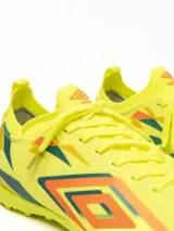 Championes de fútbol Umbro, color negro con detalles en fucsia, turquesa y plateado. Diseño con cordones y suela de goma para césped artificial.