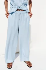 Pantalón celeste de tiro alto con cintura elástica, bolsillos delanteros y pernera ancha.