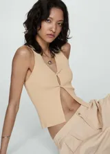 Pantalón de vestir color beige, de tiro alto, corte wide leg, con cintura elástica, pliegues frontales, cierre de cremallera y botón, y bolsillos laterales.