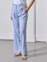 Pantalón celeste a rayas verticales, de lino, corte wide leg y tiro alto con botones decorativos.