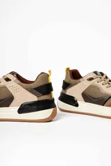 Zapatillas deportivas marrones con detalles en beige, negro y amarillo.