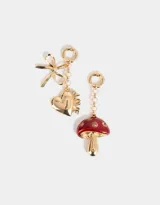 Set de dos charms dorados intercambiables para colgar en carteras o pulseras. Uno con forma de corazón con la palabra 'Love' y un moño, y otro con forma de hongo esmaltado en rojo con strass.
