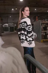 Cardigan tejido de lana color crudo con diseño geométrico en negro, cierre frontal y cuello redondo.