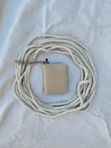 Billetera pequeña de cuero color beige con textura croco, forrada, con cierre metálico y pulsera de cuero.