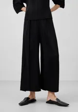 Pantalón palazzo negro con textura crinkle, cintura elástica, godets centrales y pierna ancha.