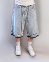 Bermuda de jean celeste matizado, corte baggy, con cordón ajustable en la cintura y detalle artesanal visible en el bajo.