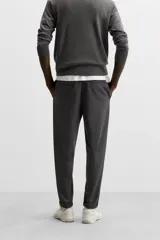 Pantalón negro de corte cropped, con cintura elástica ajustable con cordón, bolsillos laterales y traseros de vivo. El bajo tiene terminación con vuelta.