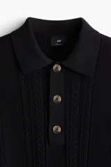 Remera polo negra de manga corta en punto trenzado con cuello clásico, tapeta de botones y bajo recto.