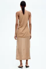 Musculosa larga color beige en tejido de punto transparente con lino en la trama. Modelo ajustado con escote en U y costura decorativa adelante y atrás.
