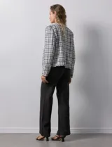 Chaqueta en tejido tweed a cuadrillé blanco y negro, marca Nanette. Cuello a la base y abertura central. Delantera con bolsillos aplicados. Manga larga, puño con botones. Terminación desflecada. Forro interno.