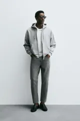 Jeans de denim de algodón, color negro lavado, con tiro medio, corte ajustado en cadera y muslos, y pierna que se estrecha hacia el tobillo. Presenta cinco bolsillos y cierre frontal con cremallera y botón.