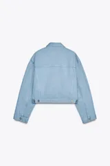 Chaqueta cropped de denim celeste claro, con cuello solapa, manga larga con puños y bolsillos de plastrón en el pecho. Cierre frontal con botones metálicos.