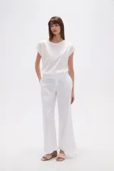 Pantalón blanco de algodón con calce recto y tiro bajo. La tela presenta bordados tipo calado (broderie) a lo largo de toda la prenda.