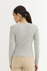 Remera de manga larga ajustada al cuerpo, con cuello redondo y estampado de rayas horizontales blancas y negras.