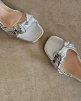 Sandalia plateada de cuero vacuno con taco cuadrado de 6 cm y tira delantera con nudo.