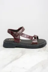 Sandalias de cuero color marrón con textura tipo cocodrilo, plataforma plana y tira ajustable con hebilla.