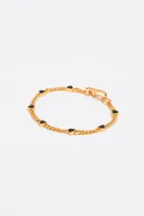 Pulsera dorada de eslabones con dijes de corazón esmaltados en negro.