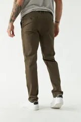 Pantalón chino color beige, de corte slim, con bolsillos laterales y traseros. Se ajusta a la cintura con cinturón de cuero marrón.