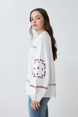 Camisa blanca con bordados florales en tonos rosa, azul y verde.