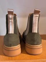 Bota Chelsea color verde oliva, con elásticos laterales en color beige, suela plana de goma color caramelo y tirador trasero.