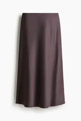 Pollera midi color marrón con leve brillo y caída suave. Modelo de tiro alto con elástico oculto en la cintura y leve vuelo en el bajo.