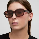 Lentes de sol unisex modelo Adisa, con montura gruesa de forma cuadrada y patillas robustas. El color de la montura es marrón oscuro (maroon) y los lentes son de color marrón.