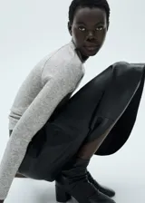 Remera de tejido fluido color gris jaspeado, con cuello redondo y mangas largas. De corte recto y sin cierre.