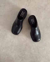 Zuecos marrones de cuero sintético con suela y taco cuadrado negros.