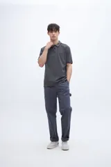 Chomba blanca de algodón con cuello clásico, media cartera de botones, bordado con la palabra 'Uniform' en el pecho y puños con rayas azul marino y rojo.