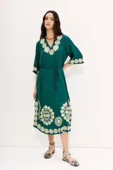 Vestido tipo túnica largo midi de viscosa color verde esmeralda con bordados florales en color crema. Tiene mangas al codo y lazo de ajuste en la cintura.