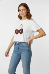 Remera blanca de algodón con estampado de cerezas, de corte crop, manga corta y cuello redondo.