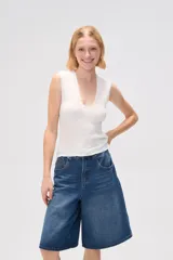 Remera blanca de poliéster con textura arrugada, breteles anchos y escote en V profundo.