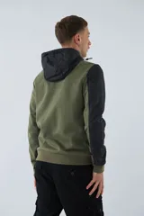 Campera verde militar para hombre con capucha ajustable, cierre frontal completo, bolsillos laterales con cierre y logo estampado en el pecho. Presenta detalles en negro en la parte superior del pecho, hombros y mangas.