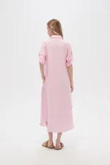 Vestido camisero midi negro de corte holgado, con cuello camisero, mangas cortas con trabillas, cierre frontal con botones, bolsillo en el pecho y bolsillos laterales.