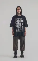 Remera negra de algodón con cuello redondo y calce oversize. Estampado frontal con diseño de plantas y texto 'Neurobotánica: El Código Raíz de la Vida'.