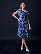 Vestido midi de gasa con estampado floral azul sobre fondo negro, torso drapeado y forro interno a tono.