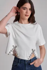 Remera blanca de algodón con cuello redondo y mangas cortas. Presenta apliques de strass en los laterales del ruedo.