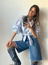 Camisa celeste a rayas blancas con mangas abullonadas y nudo en la parte delantera.