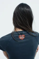 Remera azul de algodón con efecto lavado, cuello redondo y mangas cortas. Estampado frontal con un oso Care Bear y la frase "I don't do mornings!".