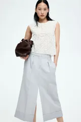 Top sin mangas color blanco, de tejido transparente con diseño bordado tono sobre tono en nudo francés. Modelo con cuello redondo y cierre oculto con cierre de corchete atrás.