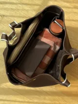 Bolso negro tipo tote de neopreno con bolsillo interno de red, sobre haciendo juego y gancho para sujetarlo.