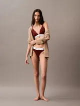 Sostén triangular Calvin Klein de la línea Modern Cotton, color rojo borgoña, con breteles finos regulables y banda elástica blanca con logo de la marca.