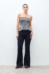 Top strapless (sin tirantes) de mujer, ajustado al cuerpo con efecto fruncido (smock) en todo el torso y un pequeño volante en el ruedo inferior. Presenta un estampado de cebra en blanco y negro.