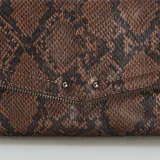 Bolso tipo sobre en estampado de piel de serpiente, con cadena para llevar como bandolera.