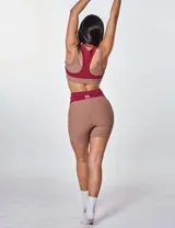 Conjunto deportivo marrón con detalles en color borgoña, compuesto por un top deportivo con logo "bk." y unos shorts de ciclista de tiro alto.