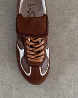 Sneakers bajas de cuero vacuno color bordó con suela marrón.