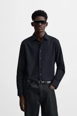 Camisa blanca de corte regular, cuello italiano, manga larga con puños abotonados y cierre frontal con botones.