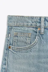 Pantalón de jean azul oscuro, de corte wide leg y tiro medio, con cinco bolsillos y cierre frontal con cremallera y botón metálico.