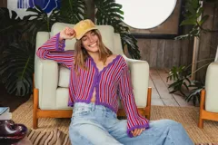 Blusa de tejido de punto con rayas verticales rojas y blancas sobre fondo violeta, con escote en V y mangas largas acampanadas.